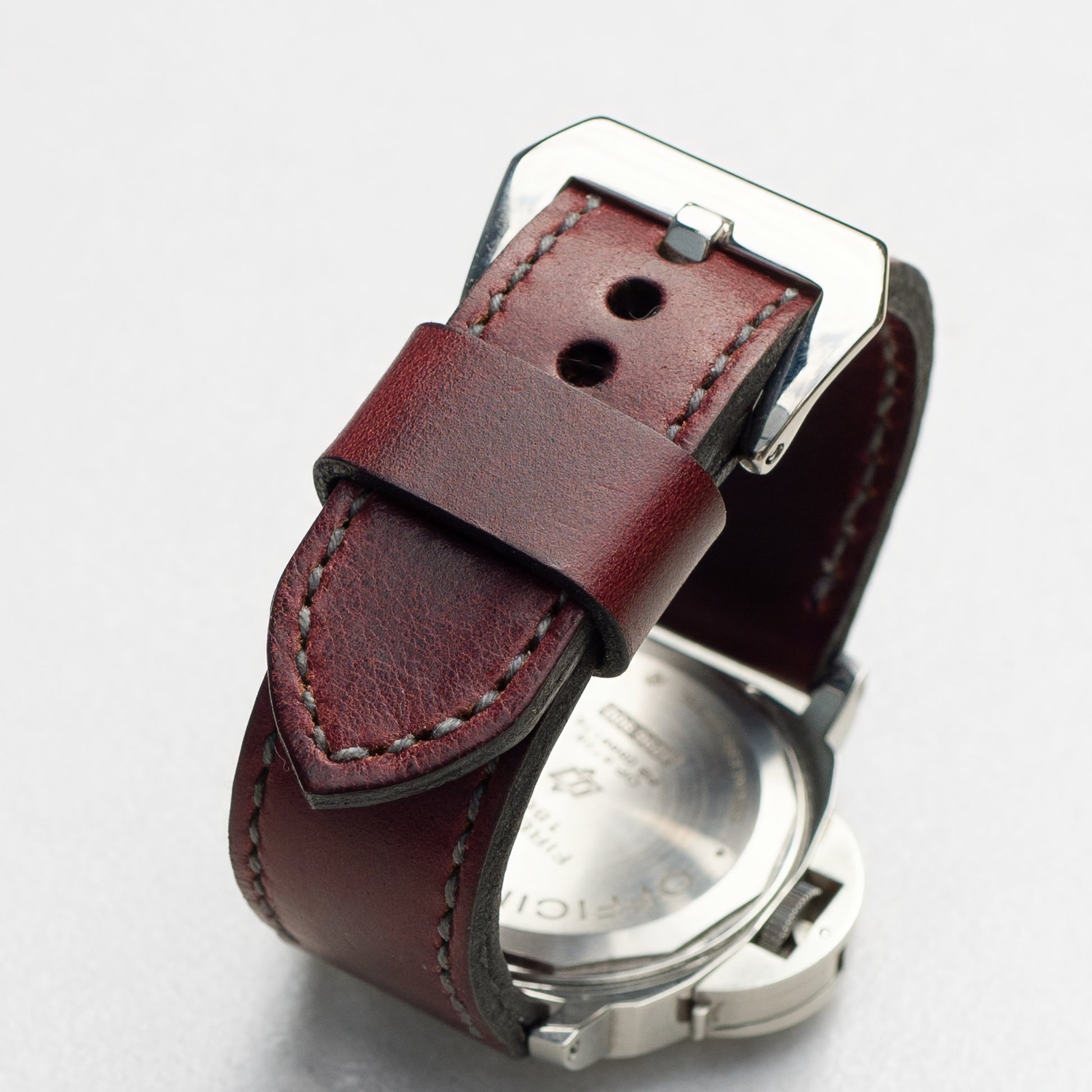 Burgundy leather watch strap with grey stitching and polished steel buckle