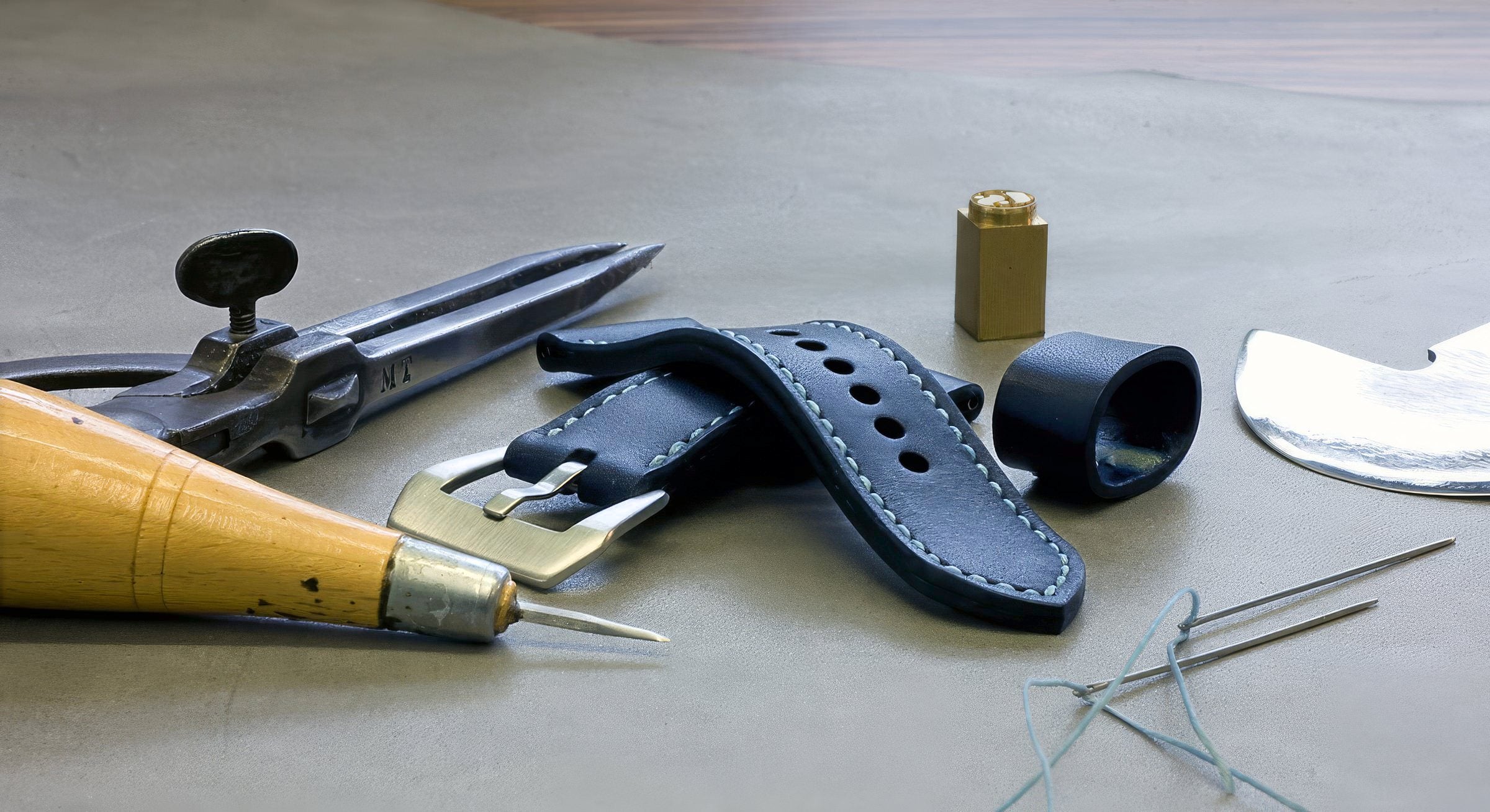 Blue leather watch strap with leatherwork tools on a workbench