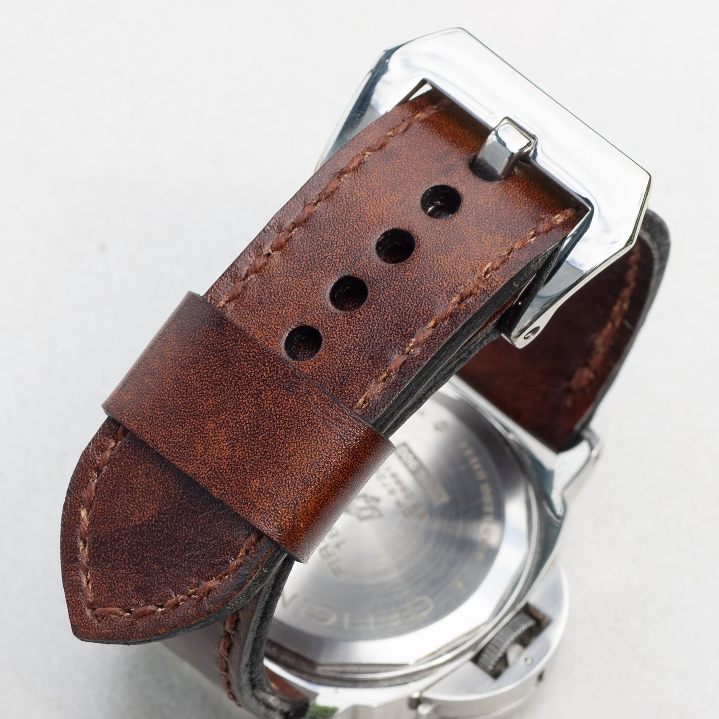 Mahogany leather watch strap with light brown stitching and polished steel buckle