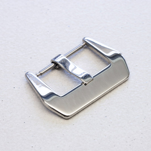 A polished stainless steel watch strap buckle with a brushed finish, shown on a light textured background.