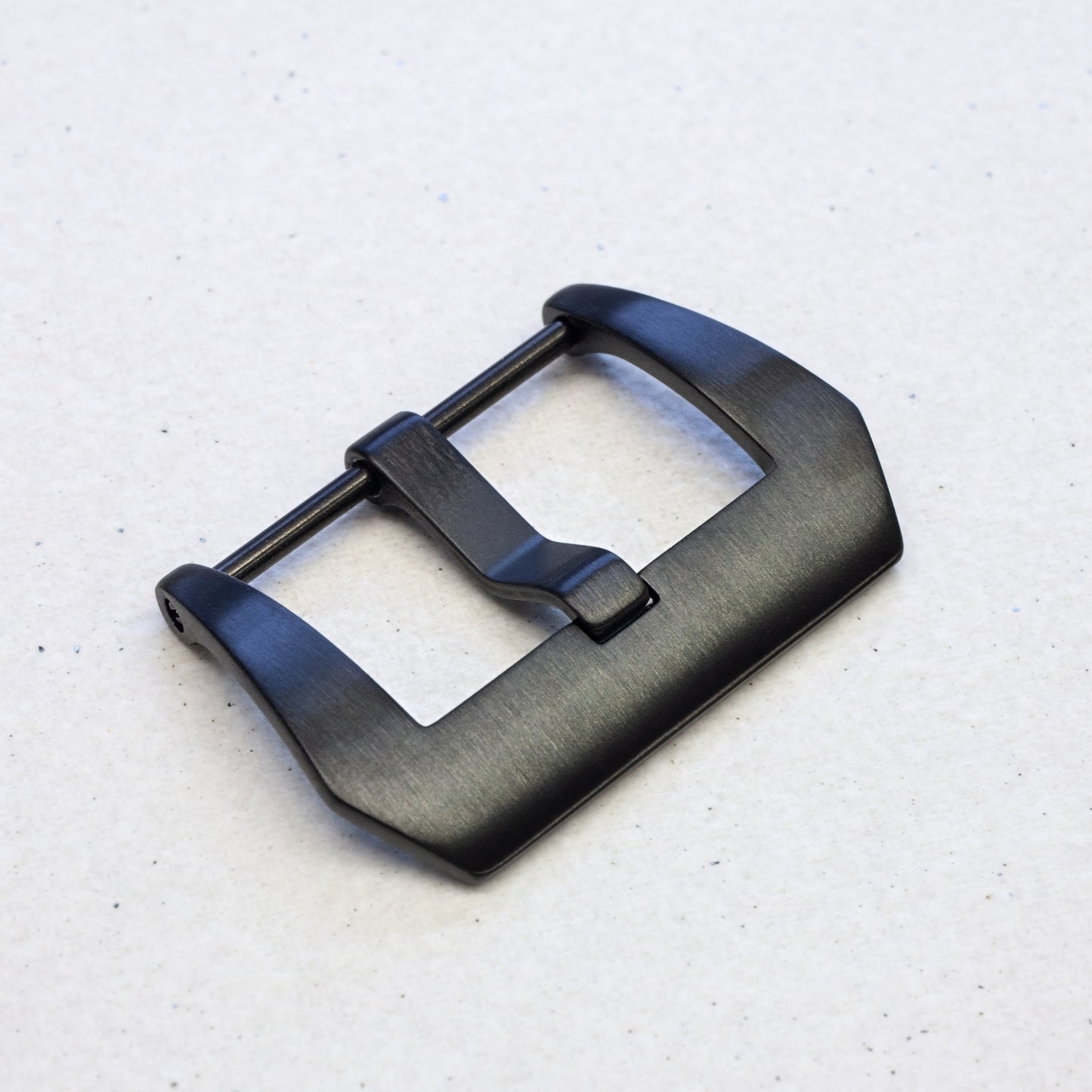 a black pvd stainless steel watch strap buckle against a light background