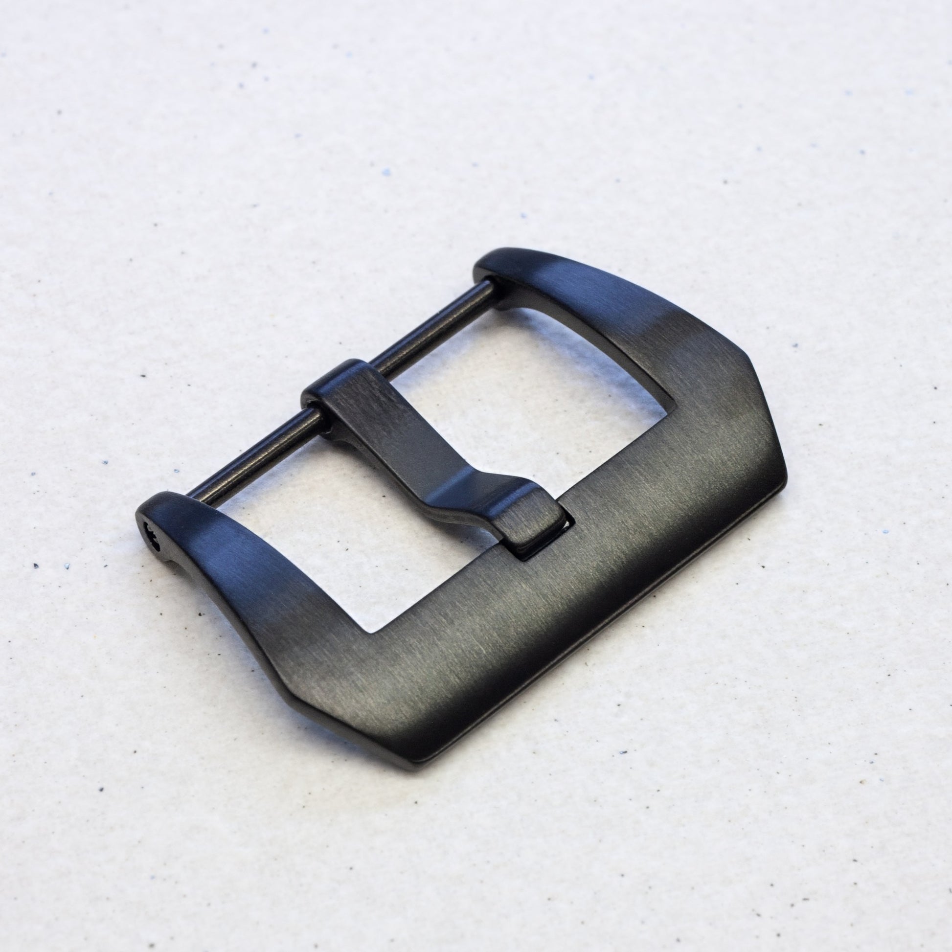 a black pvd stainless steel watch strap buckle against a light background