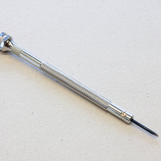 A silver precision screwdriver with a textured knurled handle and a fine black tip, photographed diagonally on a light textured off-white background.