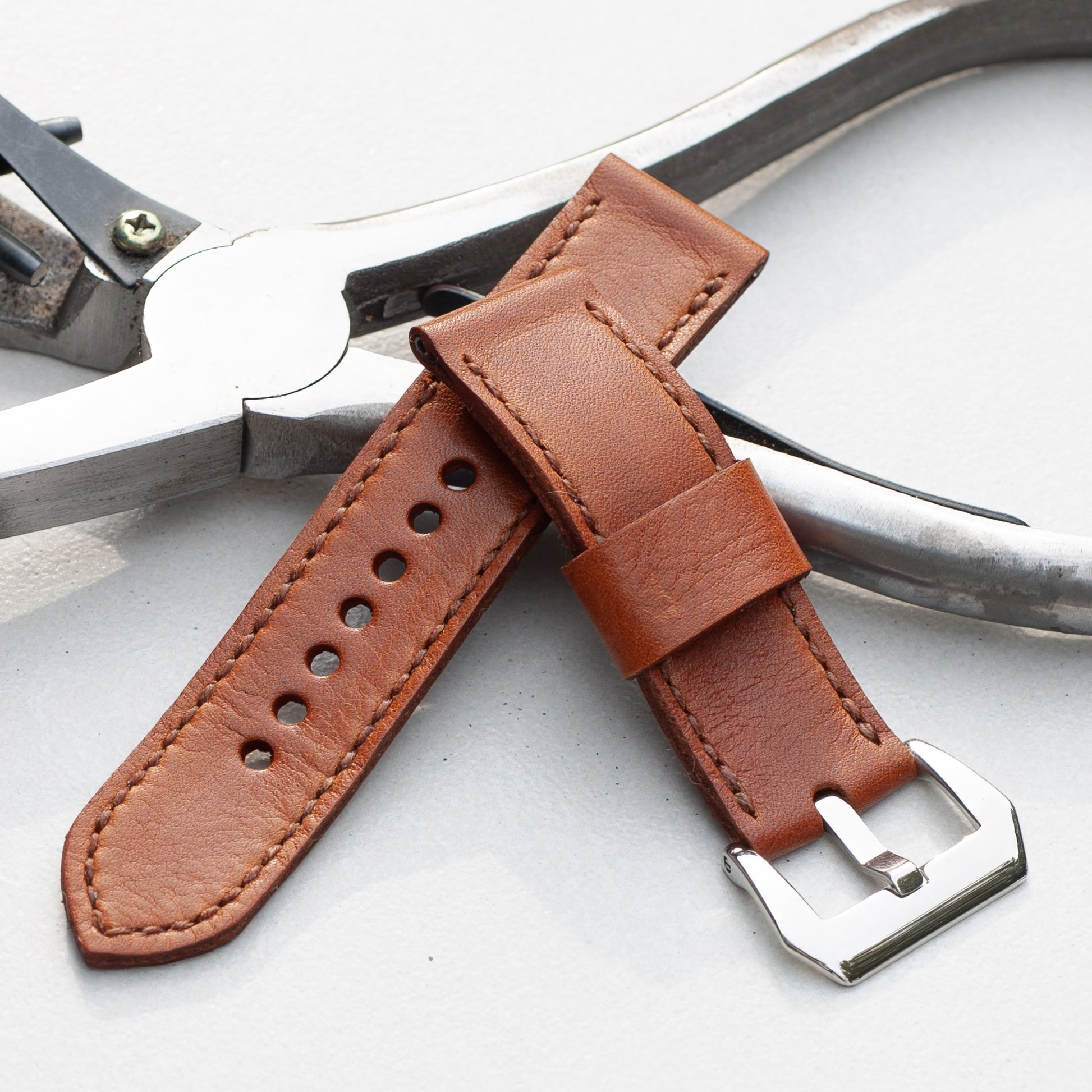 Russet leather watch strap with light brown stitching and polished steel buckle
