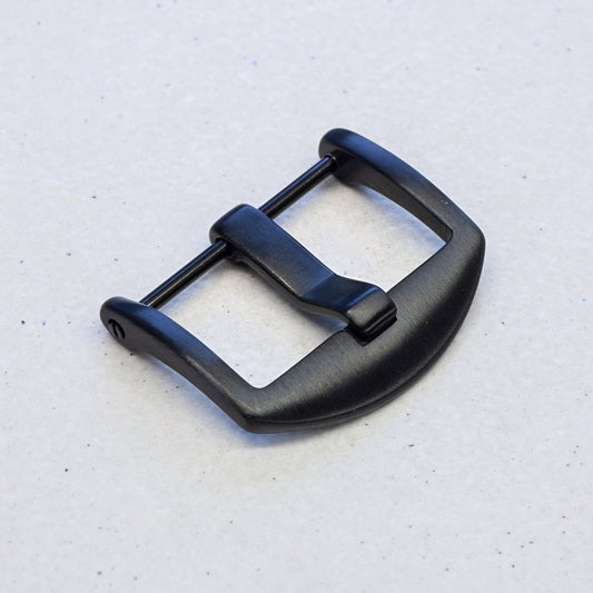 A matte black metal watch buckle with a curved D-shaped profile, shown on a light gray textured background.