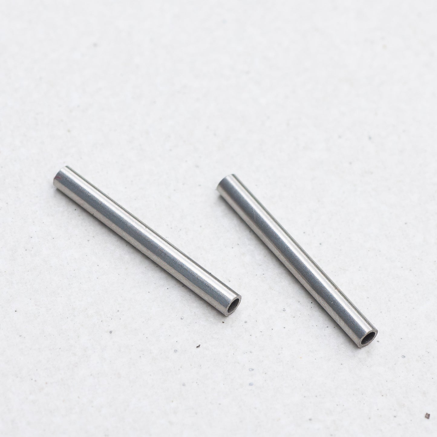 Two small Panerai tubes, placed diagonally on a light gray textured surface.