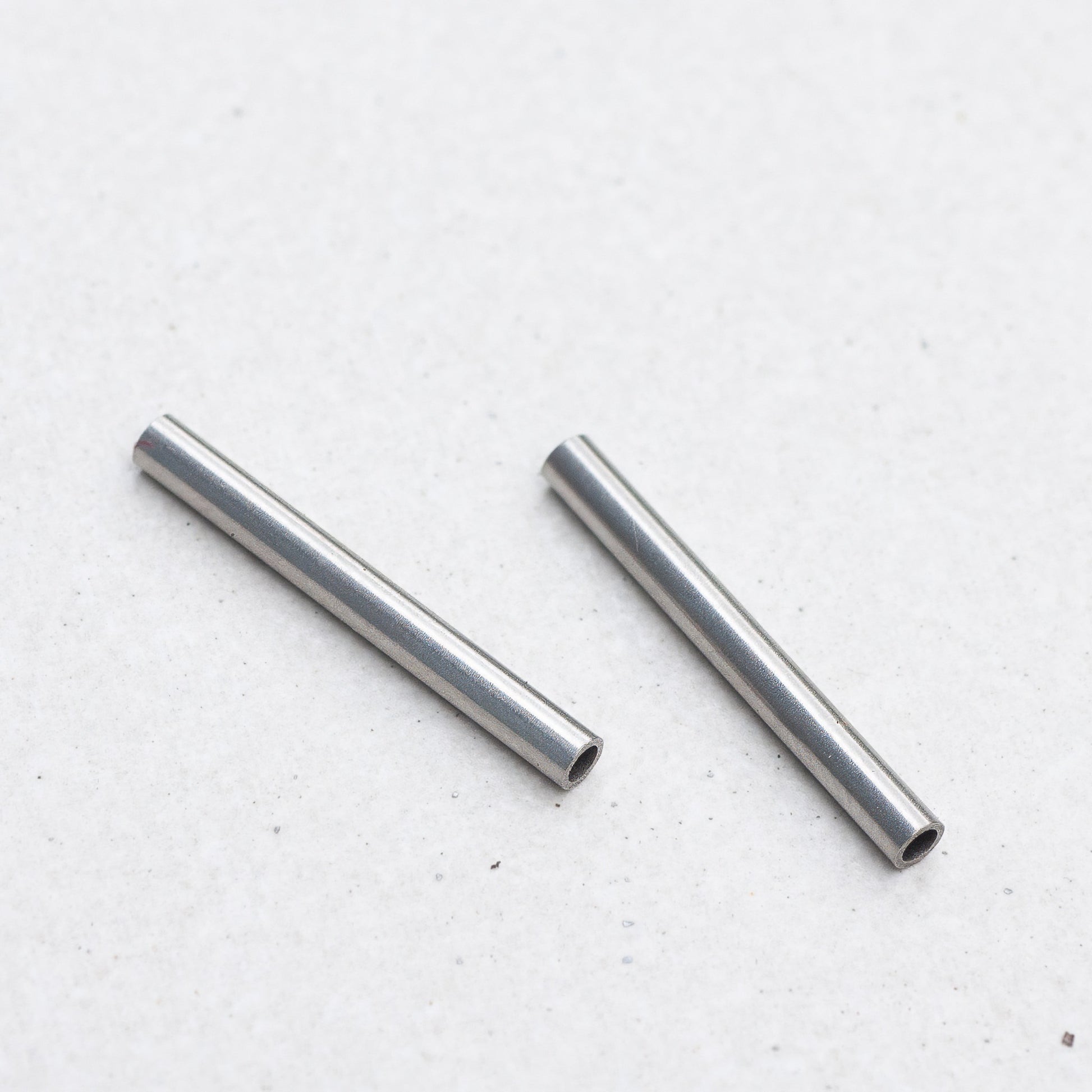 Two small Panerai tubes, placed diagonally on a light gray textured surface.