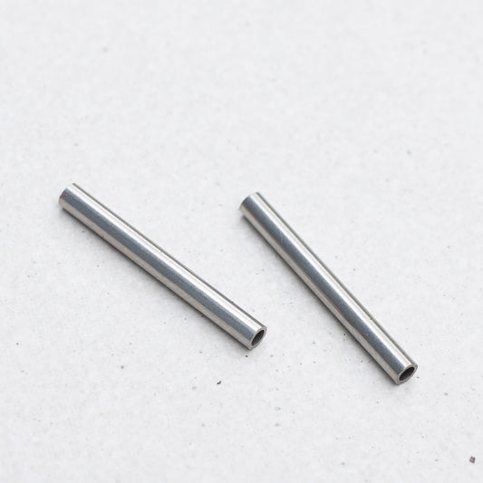 Two small Panerai tubes, placed diagonally on a light gray textured surface.