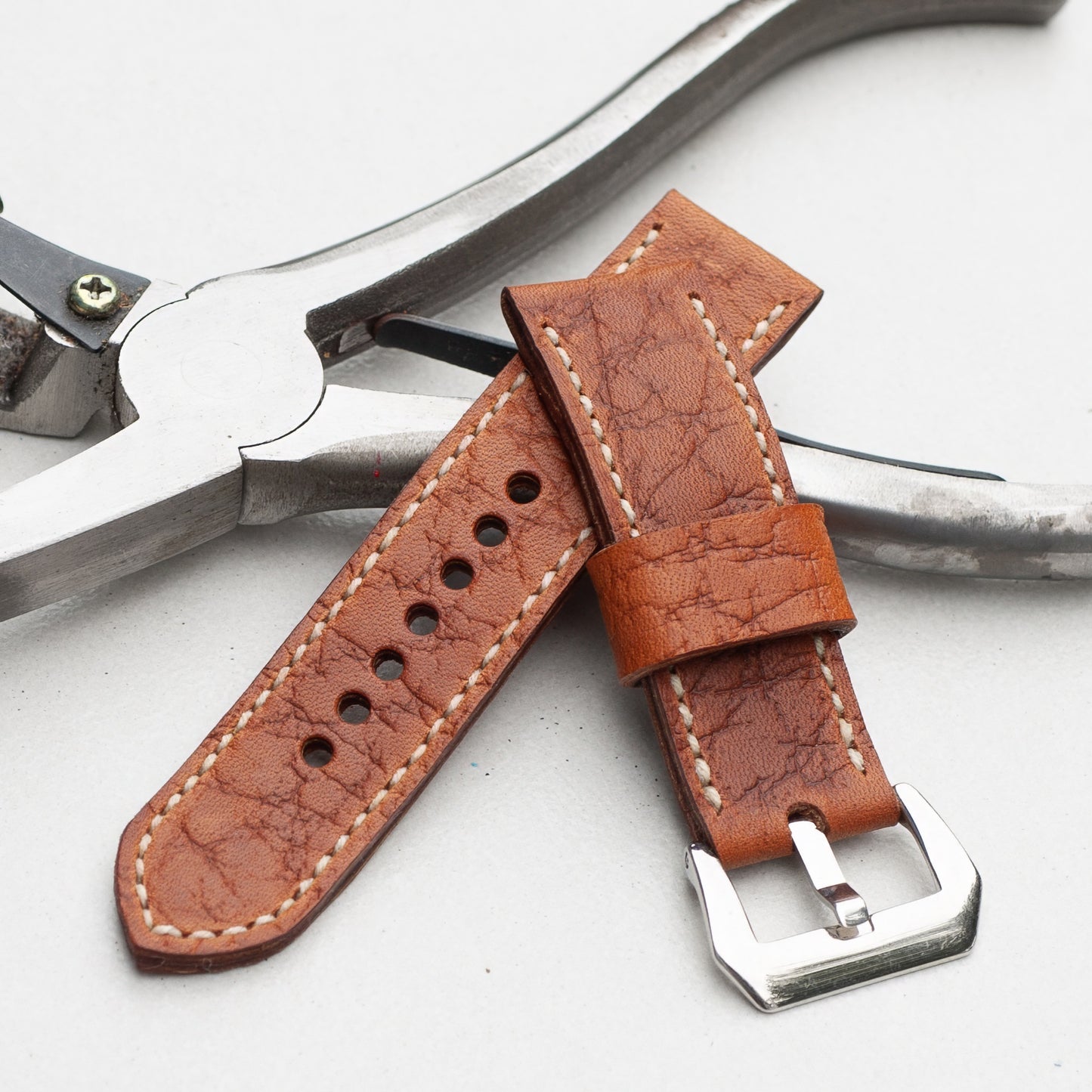 Walnut leather watch strap with natural stitching and polished steel buckle
